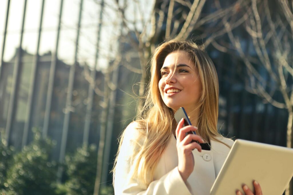 Online Tutoring: Teach from Your Couch and Earn 1 Woman Wearing White Top Holding Smartphone and Tablet